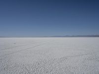 a lone person in the middle of a vast desert surface, looking to the left