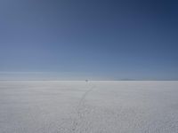 a lone person in the middle of a vast desert surface, looking to the left