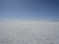 a lone person in the middle of a vast desert surface, looking to the left