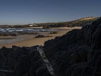 the surfer is taking advantage of the waves by himself in the distance, as others in a small group of rocks surround