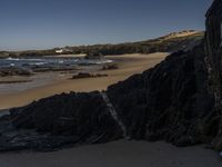 the surfer is taking advantage of the waves by himself in the distance, as others in a small group of rocks surround