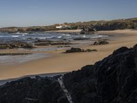 the surfer is taking advantage of the waves by himself in the distance, as others in a small group of rocks surround