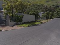 an empty street near some houses in the mountains range side view of the street, with a fenced yard and gate to it