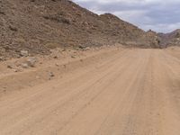 a small vehicle traveling across a barren road between some large rocks and boulders on one side