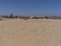 an empty beach covered with rocks and gravel, near buildings, and a sign in the distance