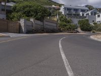 two stop signs and one direction sign in the middle of a town road near a building