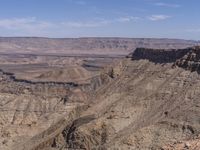 a person riding their horse up a steep canyon slope in the desert with a valley below them