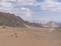 an empty desert landscape that is completely barren and full of dirt areas with mountains in the distance