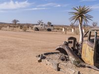 an old car and truck in a desert setting with an old style plant growing out of the back