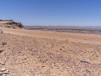 the landscape of a barren terrain has a clear blue sky over it and there are rocks on the ground