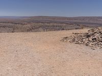 a large pile of rocks in the middle of a desert plain with mountains in the background