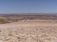 the desert is rocky with large rocks in it, along with a dry shrubland below