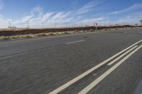 a car travels through the open desert with a highway sign in the foreground,