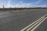 a car travels through the open desert with a highway sign in the foreground,