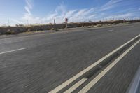 a car travels through the open desert with a highway sign in the foreground,