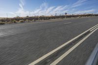 a car travels through the open desert with a highway sign in the foreground,