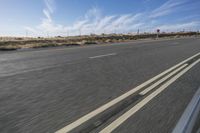 a car travels through the open desert with a highway sign in the foreground,