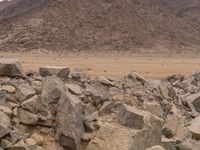 the desert landscape is littered with rocks and stones with a few hills in the background