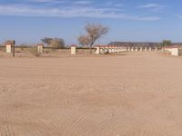 a dirt road and fence in a large desert area with houses on it and no cars on the road