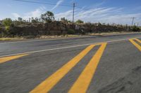 a highway with two yellow stripe lines on the road and a rock wall behind it