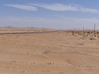 empty road near desert area with mountains in background, no people yet on it, in the distance are bushes and sparse clouds