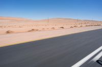 a person riding a motorcycle on the highway with desert scenery and blue sky in the background