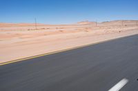 a person riding a motorcycle on the highway with desert scenery and blue sky in the background