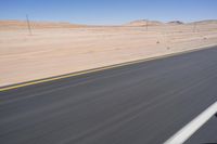 a person riding a motorcycle on the highway with desert scenery and blue sky in the background