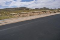 a view of a road going through the desert, with a person on a motorcycle near by