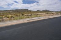 a view of a road going through the desert, with a person on a motorcycle near by