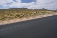 a view of a road going through the desert, with a person on a motorcycle near by