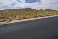 a view of a road going through the desert, with a person on a motorcycle near by