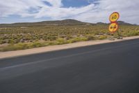 a view of a road going through the desert, with a person on a motorcycle near by