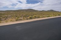 a view of a road going through the desert, with a person on a motorcycle near by