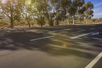 a highway with markings on the street, trees, and some dirt on the sides