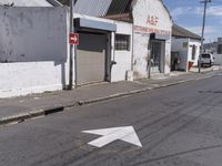 an arrow pointing in different directions in a street with some shops around the corner and cars parked along the side