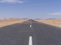 empty road near desert area with mountains in background, no people yet on it, in the distance are bushes and sparse clouds