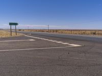 a road with two green signs above it on a clear day in the middle of nowhere