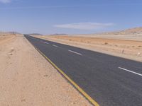 empty road near desert area with mountains in background, no people yet on it, in the distance are bushes and sparse clouds