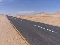 empty road near desert area with mountains in background, no people yet on it, in the distance are bushes and sparse clouds