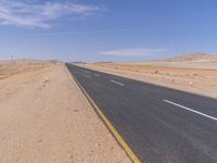 empty road near desert area with mountains in background, no people yet on it, in the distance are bushes and sparse clouds