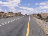 the empty street is on the rocky hill side and yellow paint shows the line of a curving road