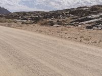 a person riding a motorcycle on a dirt road through the middle of mountains with rocks