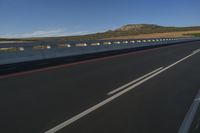 highway with long straight asphalt with mountains in background on sunny day, with cars passing