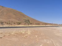 an empty road is shown in the middle of desert area with a steep mountain on both sides