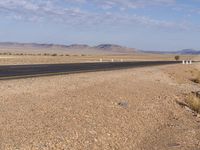 a deserted desert road with no traffic in it and the mountain in the distance is the horizon line