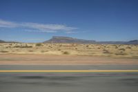 a desert area with mountains in the distance on a clear day with blue skies and clouds