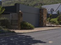 a car is parked in front of a house with a gate and stone wall to the side