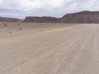 a cow walks across a deserted empty desert road while the vehicle travels in front of him