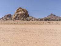 an empty, barren desert with rocks and sparse vegetation in the background under blue skies